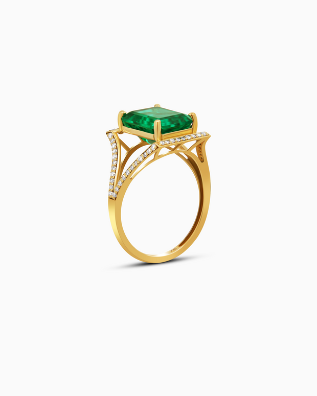 Gold ring with a green gemstone and diamond accents on a white background